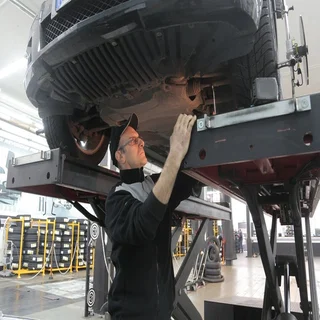 mechanic checking underbody of car