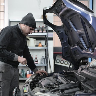 mechanic testing oil level with dip stick