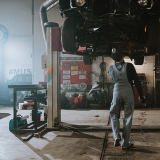 mechanic performing a visial inspection from under car