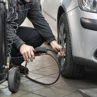 mechanic pumping up a tyre of a car